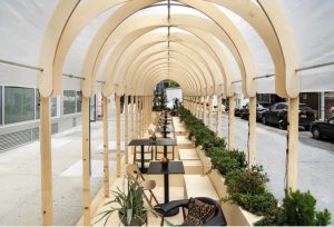 Long lacking in outside dining capabilities, NYC has undergone a radical transformation the last few months in order to accommodate the needs of bars and restaurants—and the safety and mental health of its residents. The latest destination to metamorphose parking spots into an elegant activation space, NeueHouse Madison Park looked to some of its own members, associates at Australian architectural and design firm BVN, for the modular system, Re-Ply, that now composes their new addition, The Longhouse. It’s more than an outdoor collaboration and hospitality space for the private community: it’s a demonstration of upcycled solutions for a city in need.